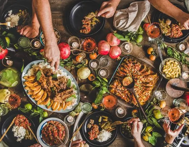 Family enjoying a catered meal together at a home celebration with South Asian dishes on the table