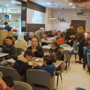 Busy restaurant dining room with guests seated at tables under pendant lights