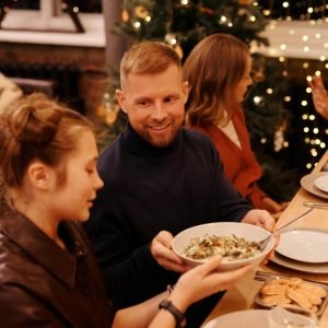 Guests passing a bowl of salad around the table at a celebration dinner with fairy lights